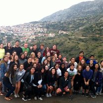 A group of students posing with a small Greek town in the background. 