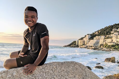 A man sitting on a rock near a beach.